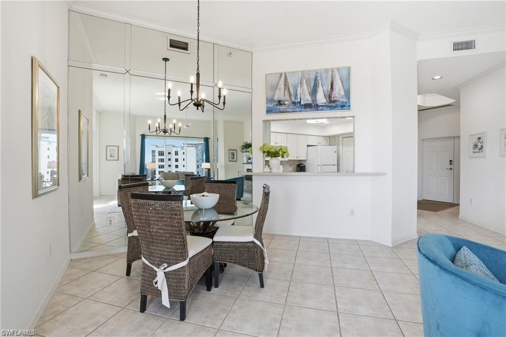 Dining area featuring tile flooring, a mirrored accent wall, and an open pass-through to the kitchen