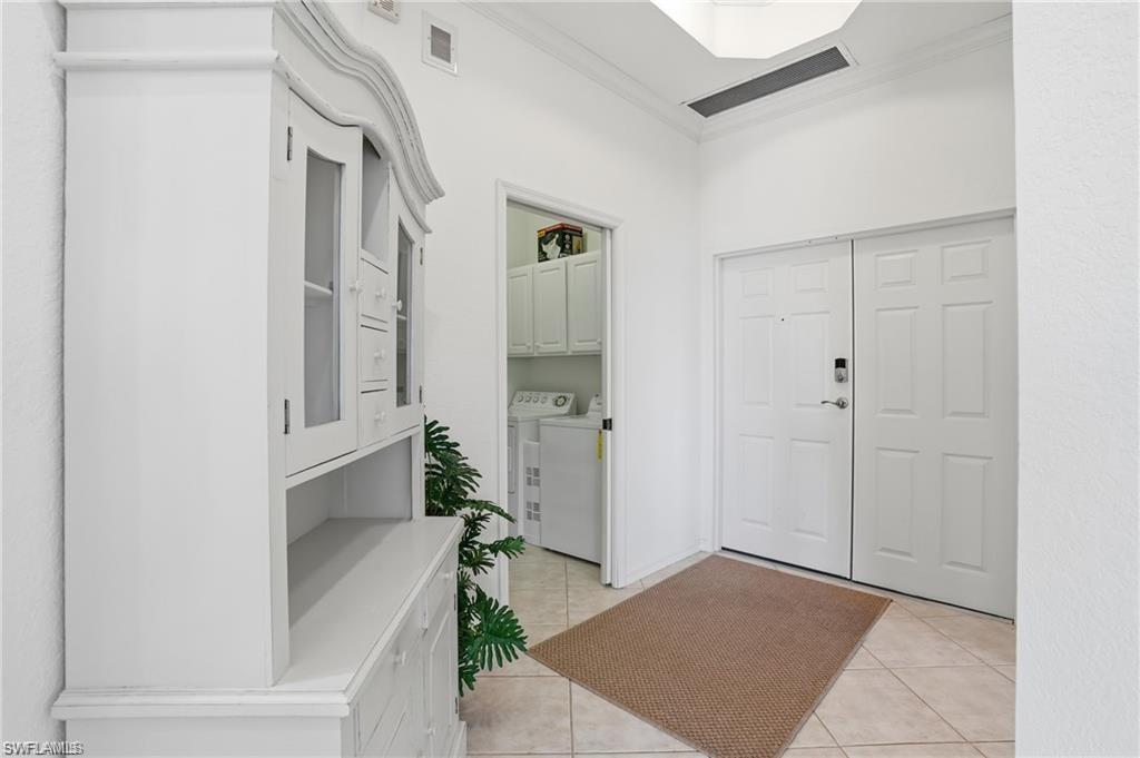 Entryway featuring tile flooring, white double doors, and a built-in hutch with glass-front cabinets