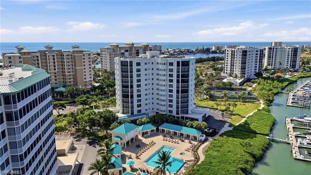 Coastal condominium property featuring multiple high-rise buildings, a marina with docked boats, and multiple swimming pools with surrounding lounge areas