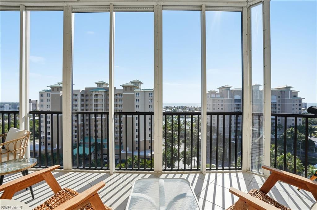 Enclosed balcony featuring floor-to-ceiling windows, white frames, black railing, and tiled flooring