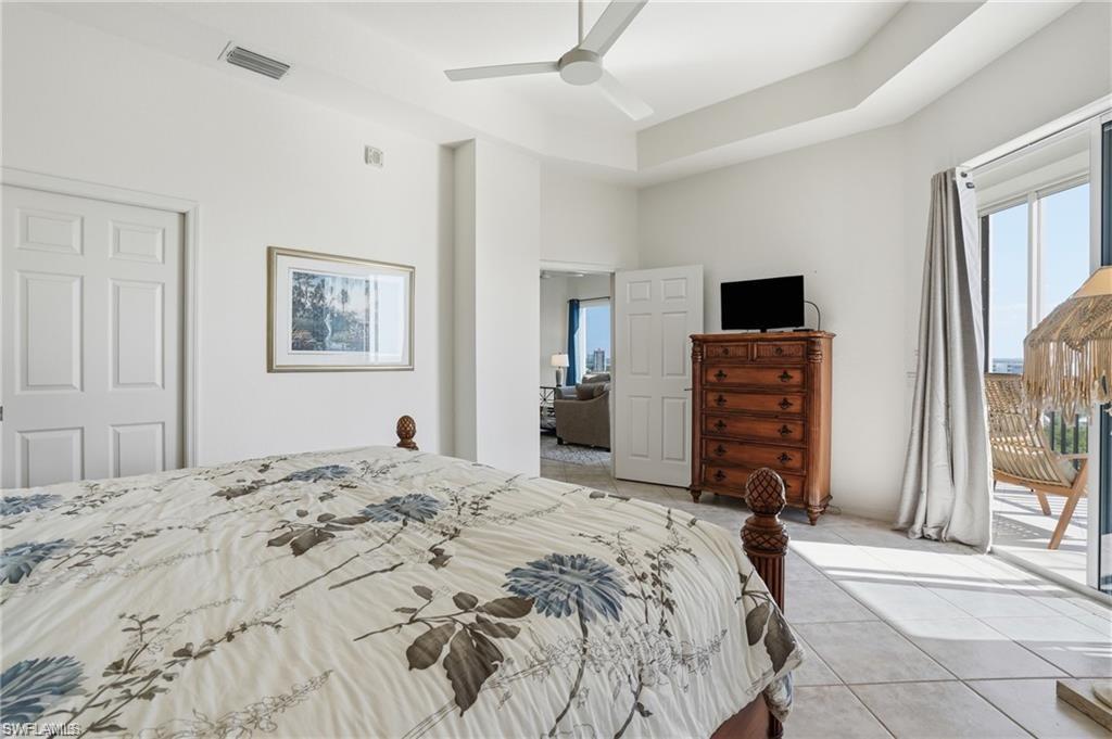 Spacious room featuring tray ceiling, ceiling fan, and large sliding glass doors leading to an outdoor area