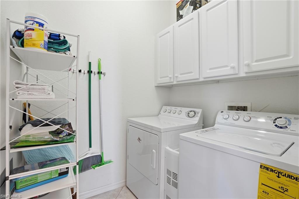 Dedicated laundry room featuring a white top-load washing machine, a white front-load dryer, and white upper cabinetry