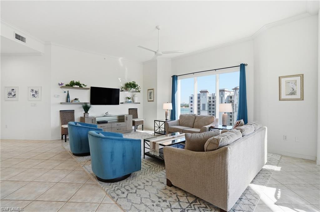 Spacious living area featuring tile flooring, a contemporary ceiling fan, and a large window with water and building scenery
