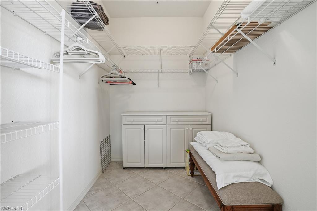 Walk-in closet featuring extensive wire shelving, hanging rods, central built-in cabinetry, and tile flooring