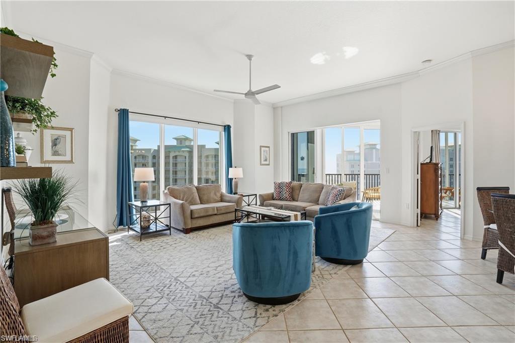 Spacious living area featuring large format tile flooring, crown molding, and a ceiling fan