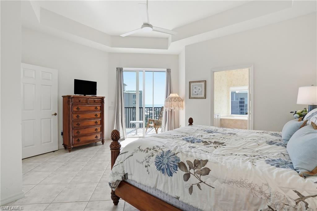 Tray ceiling bedroom with private balcony access and tile flooring