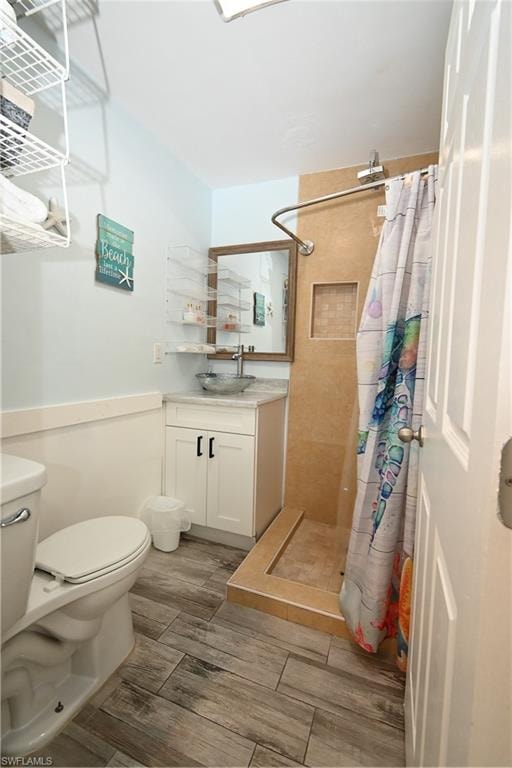 Bathroom featuring wood-finish flooring, a white vanity with vessel sink, a mirrored medicine cabinet, and a tiled shower stall with a built-in niche