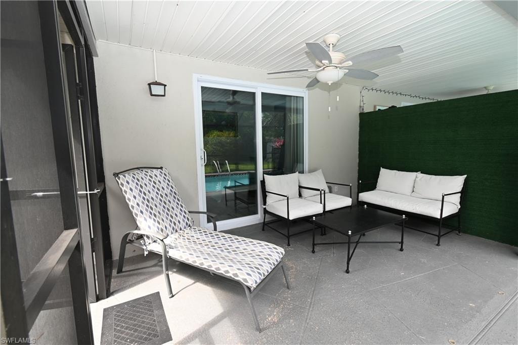 Covered outdoor patio featuring a slatted ceiling, ceiling fan, and a sliding glass door providing access to the pool area