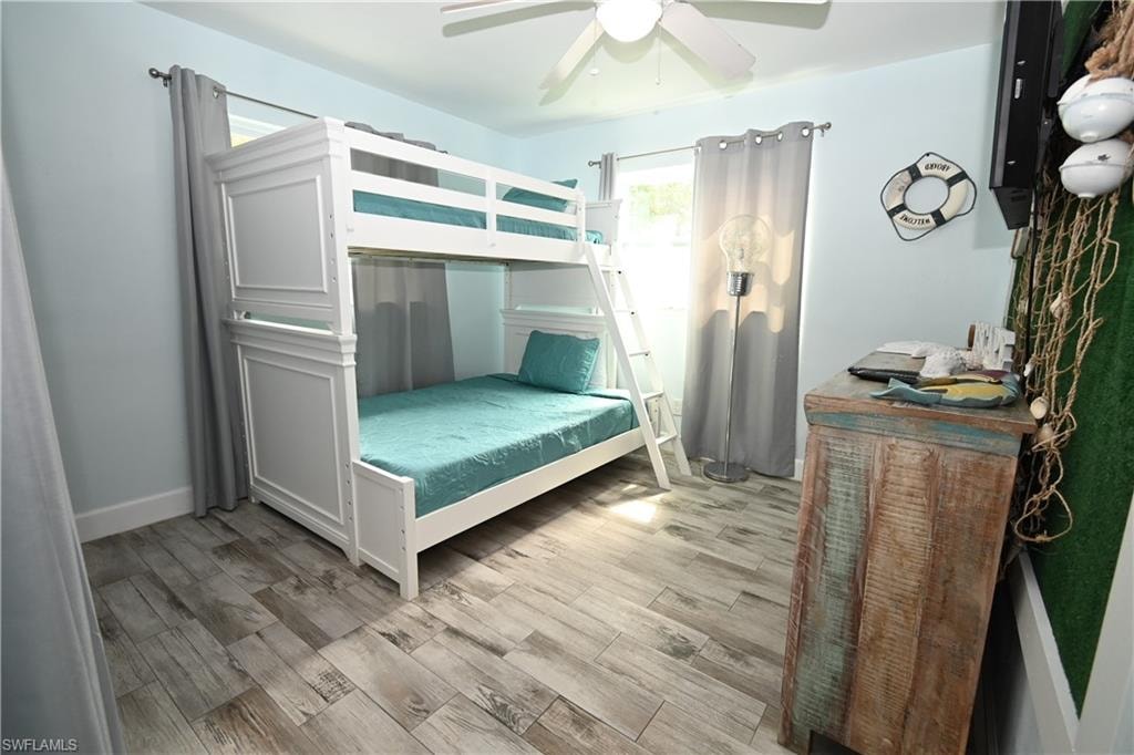 White bunk bed with a ladder, wood-finish flooring, light blue walls, and a ceiling fan