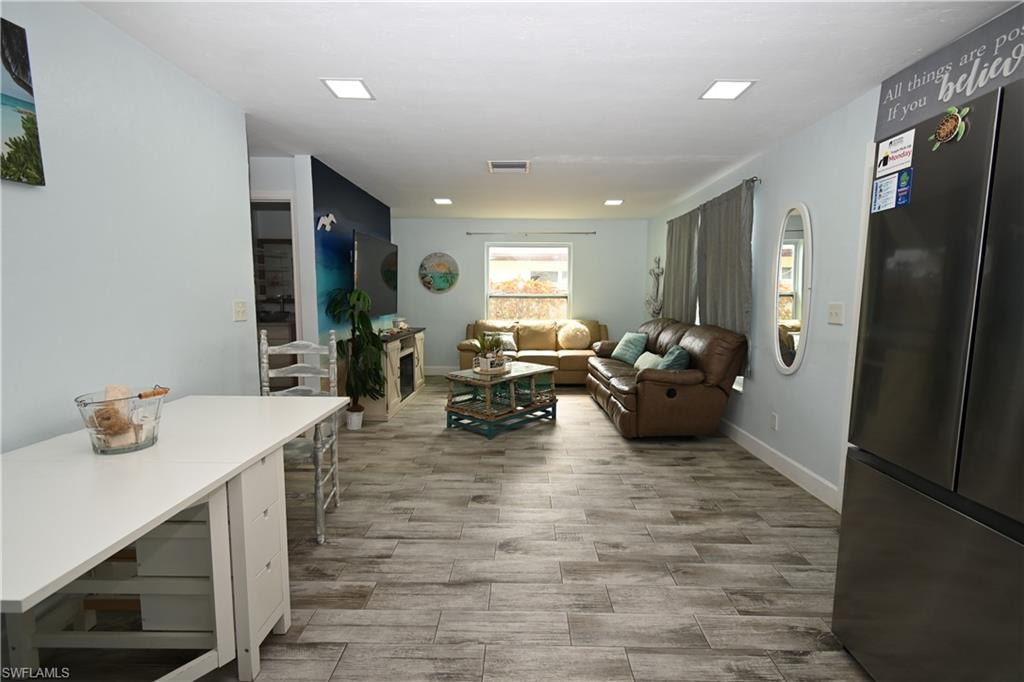Open-concept living area featuring wood-finish tile flooring, recessed ceiling lighting, and light blue wall tones