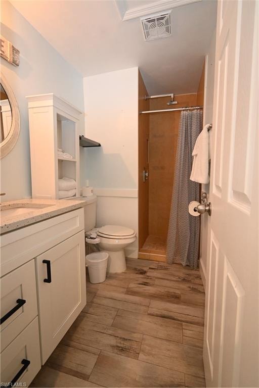 Bathroom featuring wood-finish flooring, a white vanity with black hardware, a shower with a wood-look surround, and a built-in shelving unit
