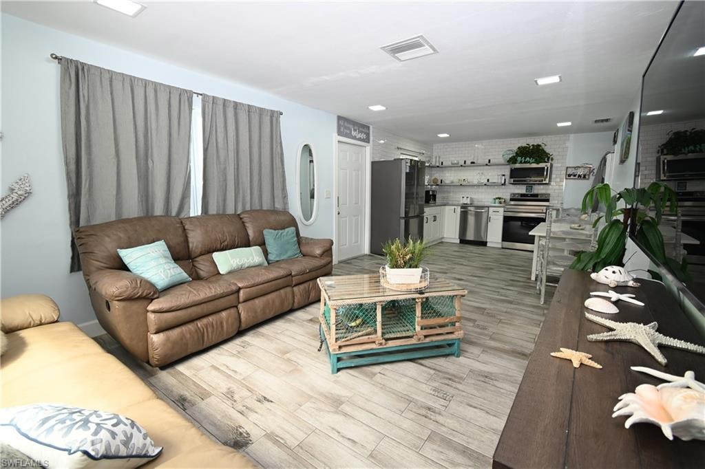 Open-concept living area featuring wood-finish flooring, recessed lighting, and a white interior door