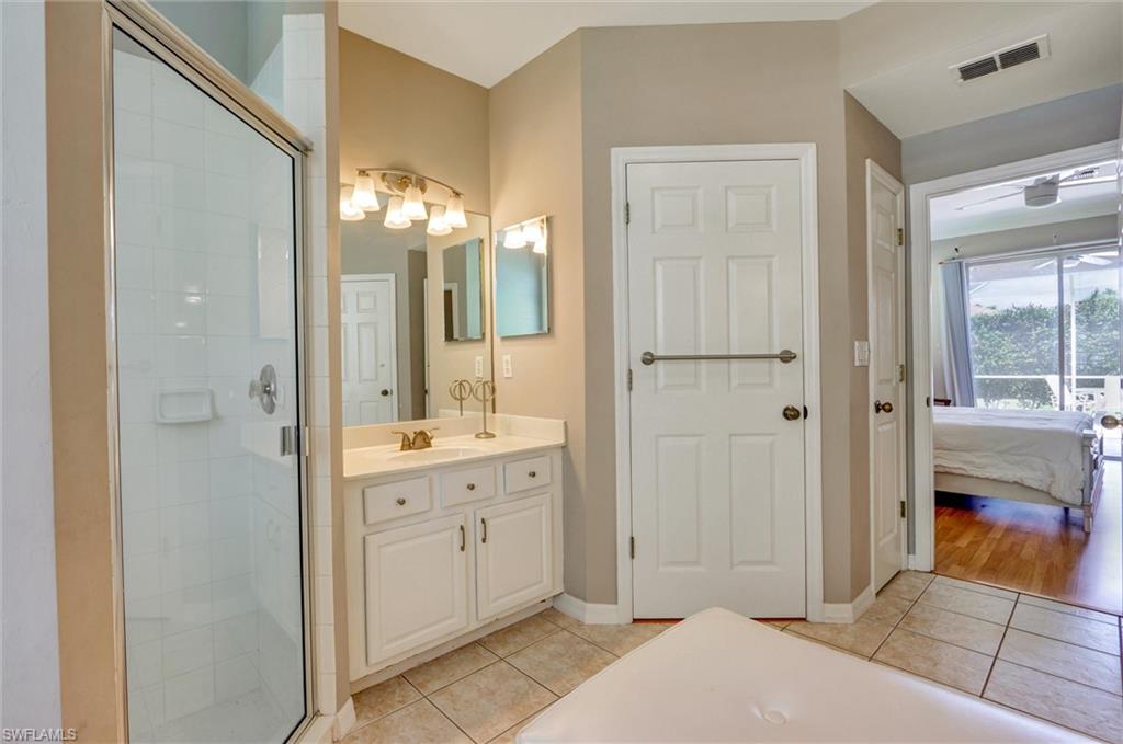 Bathroom featuring a glass-enclosed shower, single vanity with a white countertop, large mirror, and tiled flooring