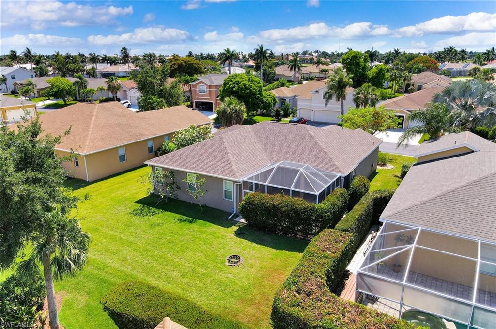 Single-story residence featuring a screened-in patio, mature landscaping, and a shingle roof
