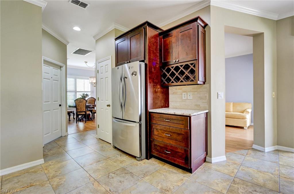 Kitchenette area featuring rich wood-finish cabinetry, built-in wine storage, a stone countertop, and a tiled backsplash