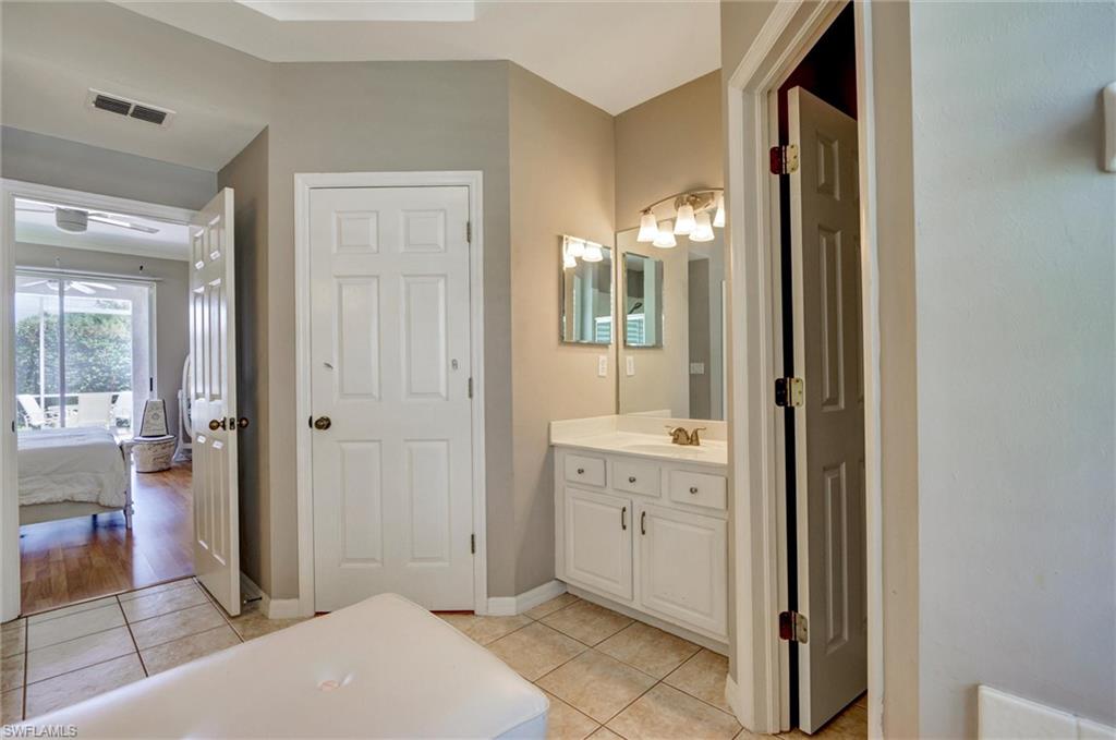Bathroom vanity with white cabinetry, a single sink, and a multi-bulb light fixture