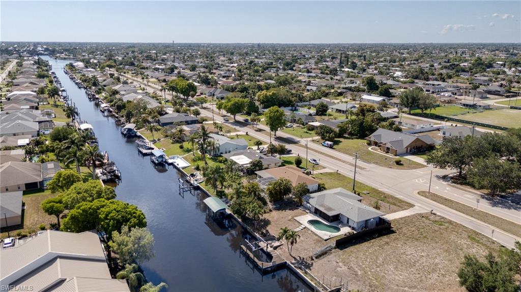 Canal-front property featuring a private boat dock and lift, mature palm trees, and an in-ground swimming pool