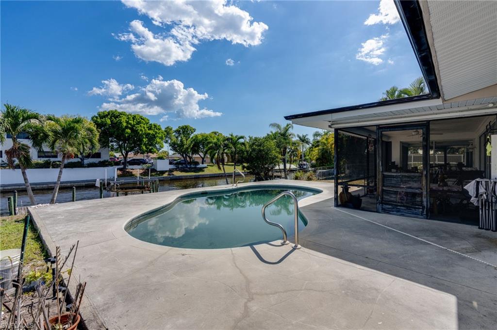 Outdoor swimming pool with a concrete patio surround and direct canal access featuring a private dock