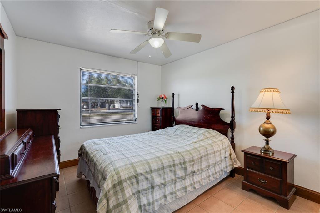 Bedroom with neutral walls, ceiling fan with integrated lighting, and tile flooring