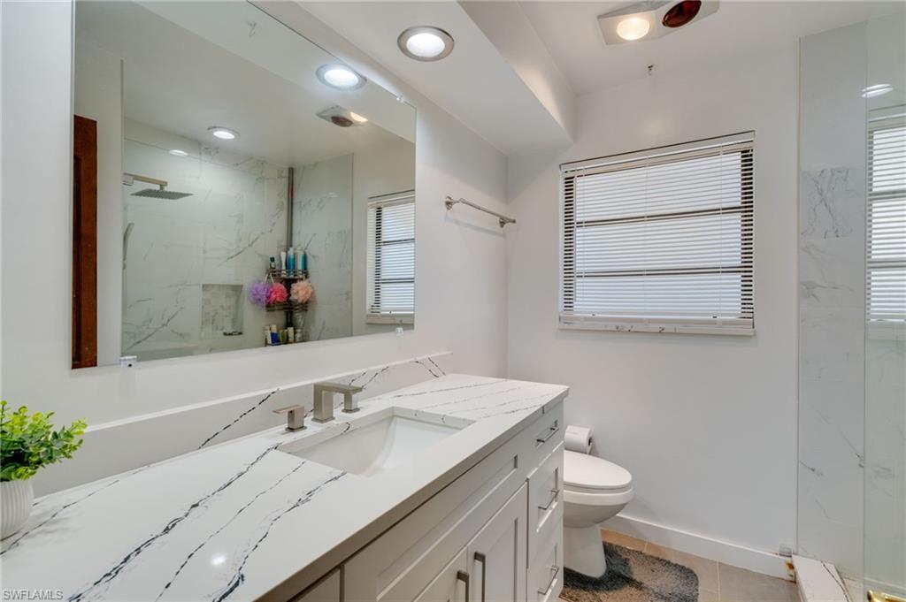 Bathroom featuring a white vanity with an integrated sink, patterned countertop, and a large wall-mounted mirror