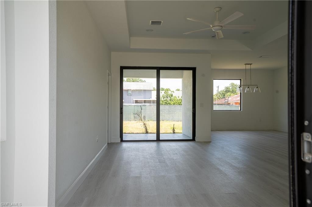Spacious interior with light wood-finish flooring, white walls, and a contemporary ceiling fan