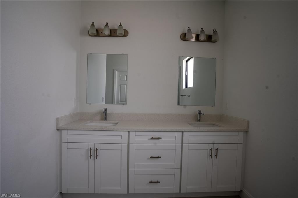 Dual vanity featuring white shaker-style cabinetry, a light-toned countertop, and undermount sinks