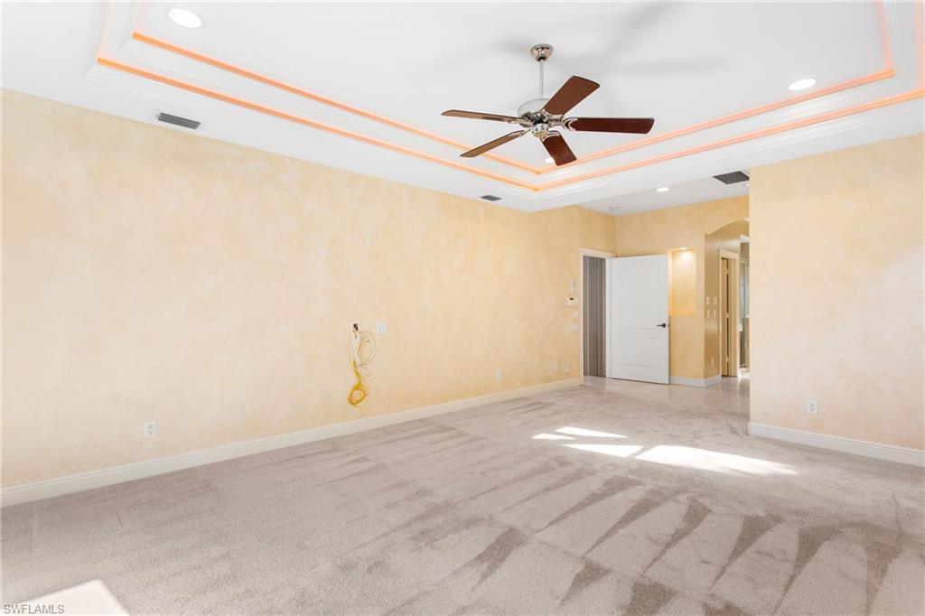 Spacious room featuring a tray ceiling with integrated lighting, recessed lighting, and a ceiling fan