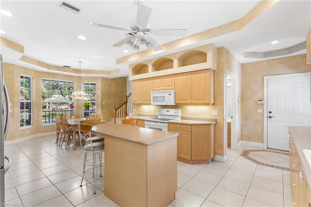 Open-concept kitchen and dining area featuring light-toned cabinetry, a central island, and white tile flooring throughout