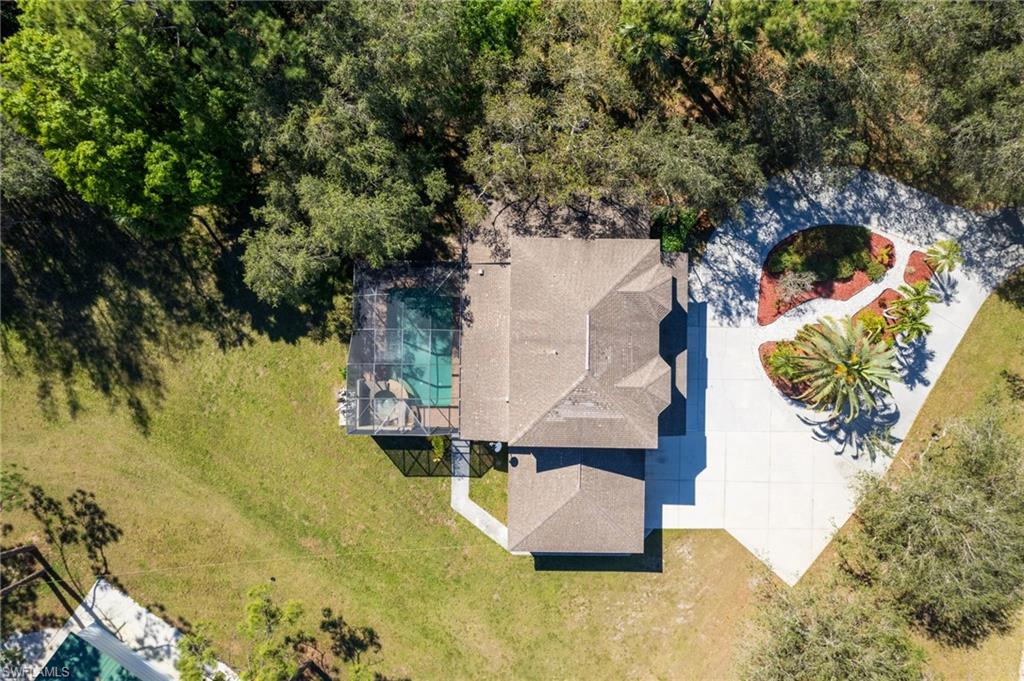 Aerial perspective showcasing a single-story residence with a multi-gabled roof and an enclosed swimming pool