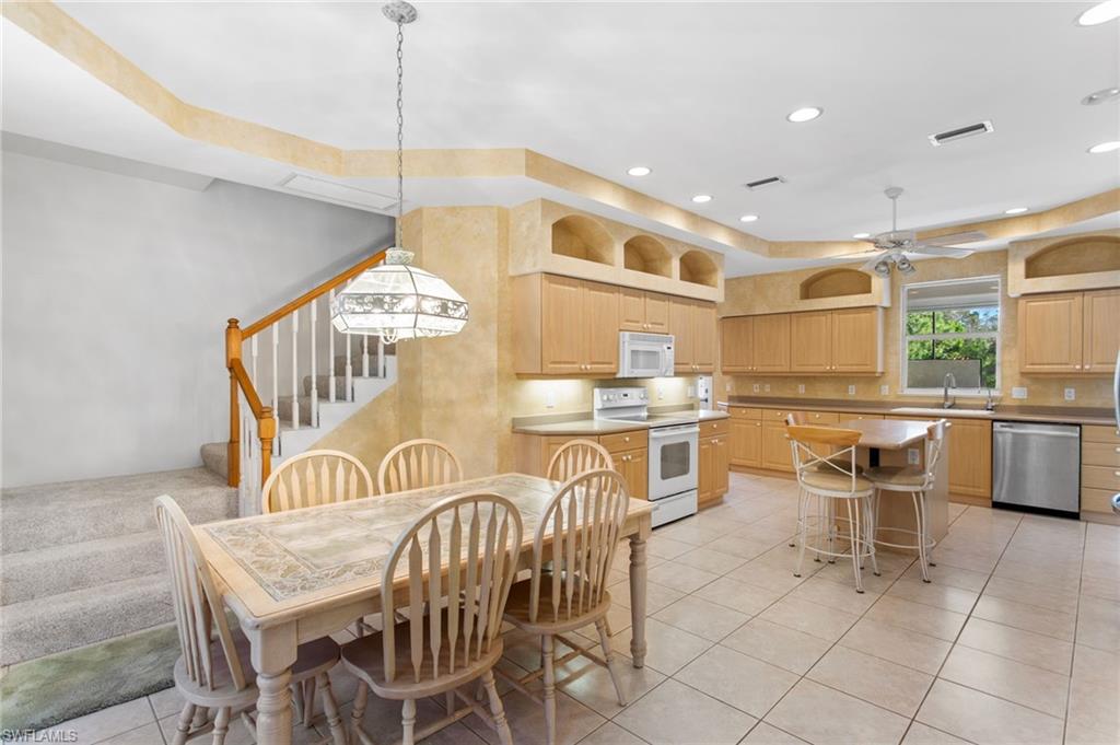 Kitchen featuring wood-finish cabinetry, tile flooring, recessed lighting, and a center island with seating