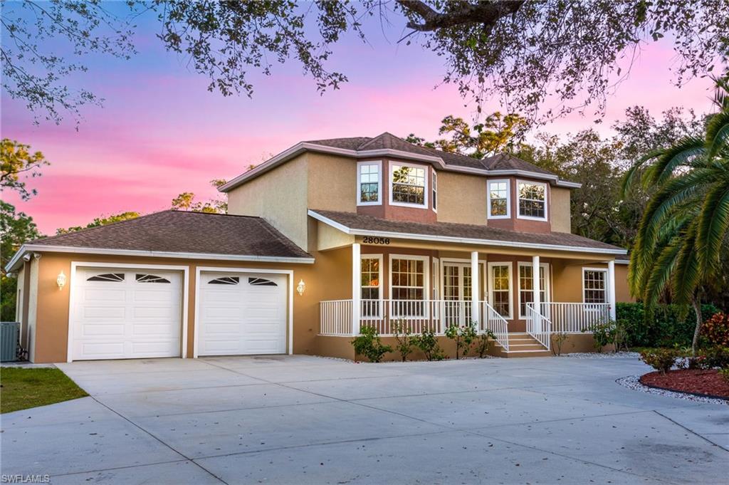 Two-story residence featuring a stucco exterior, a covered front porch with white railings, and multiple bay windows