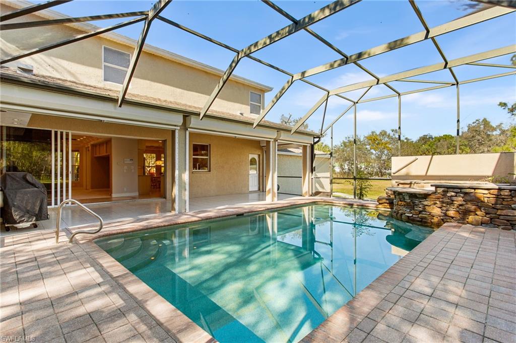 Screened outdoor living area featuring a rectangular pool with integrated spa