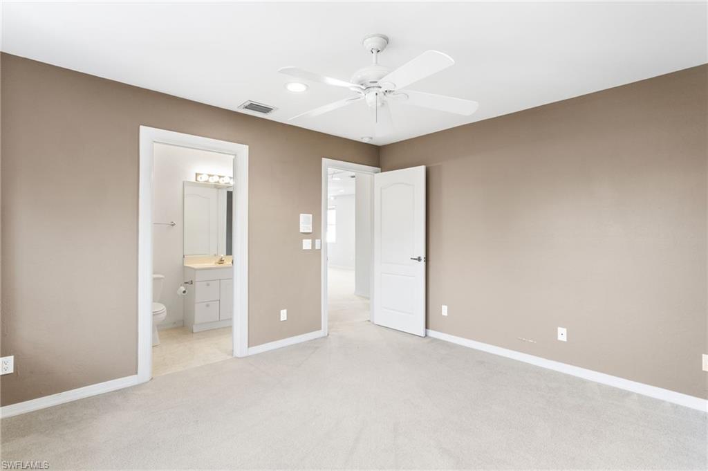 Carpeted room with neutral-toned walls, white trim, and a ceiling fan