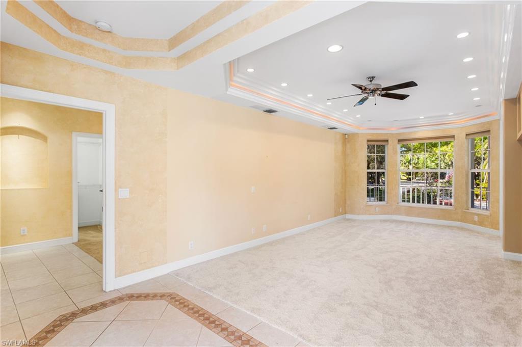 Spacious room featuring a tray ceiling with recessed lighting, a ceiling fan, and carpeted flooring