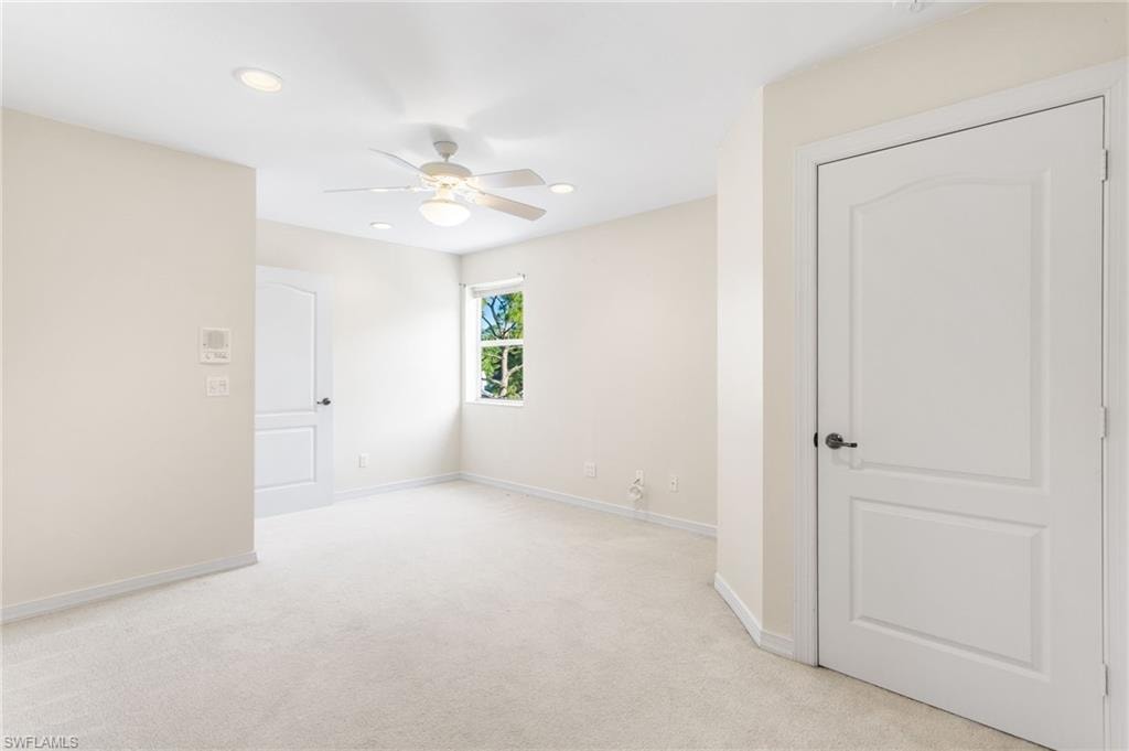 Carpeted interior space featuring light-colored walls and a ceiling fan with integrated lighting