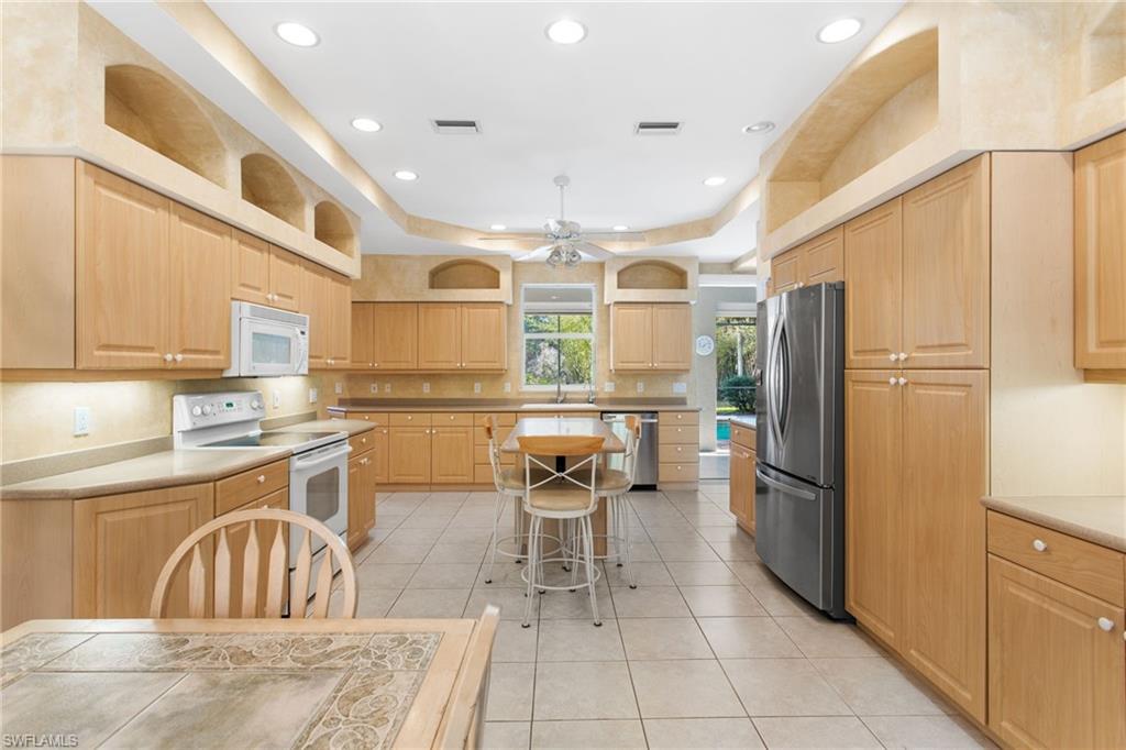 Spacious kitchen featuring extensive light wood cabinetry, recessed lighting, tile flooring, and stainless steel appliances