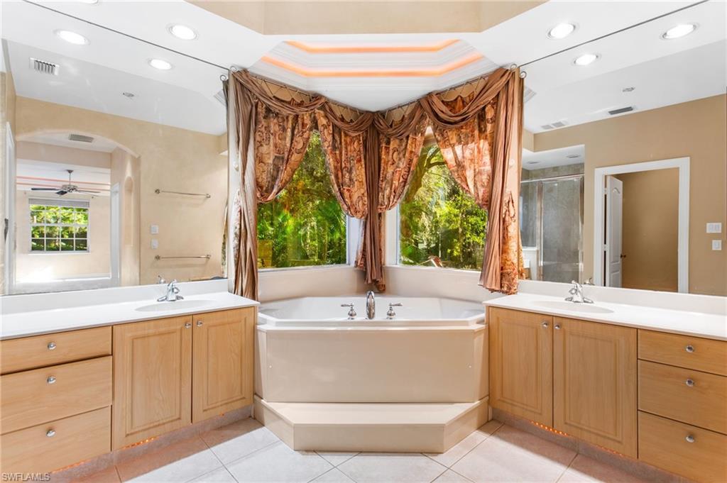 Enclosed corner soaking tub with surrounding windows and decorative drapery