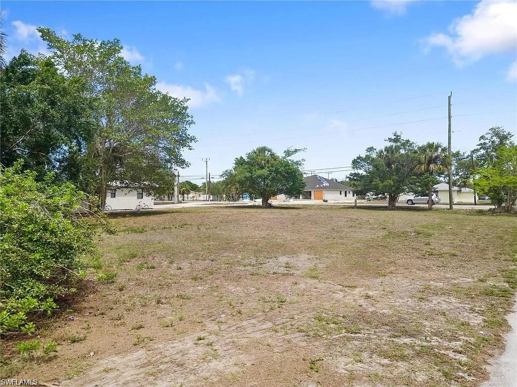 Expansive lot featuring mature trees, a clear blue sky, and ample open space