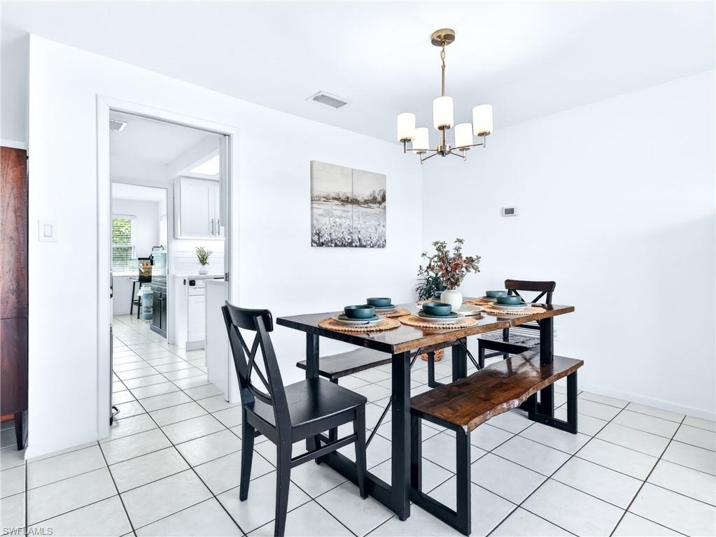 Dining area featuring white square tile flooring and a bronze five-light chandelier