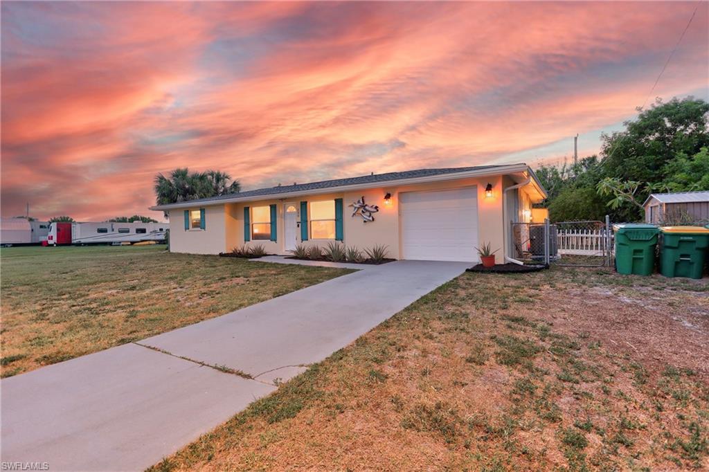 Single-story residence featuring a front-facing garage, concrete driveway, and a light-toned exterior with contrasting trim accents
