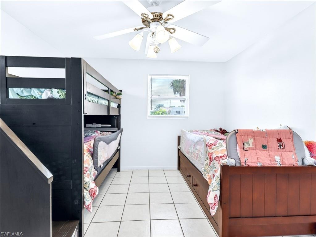 Room featuring neutral wall paint, square tile flooring, a window with blinds, and a ceiling fan with integrated lighting