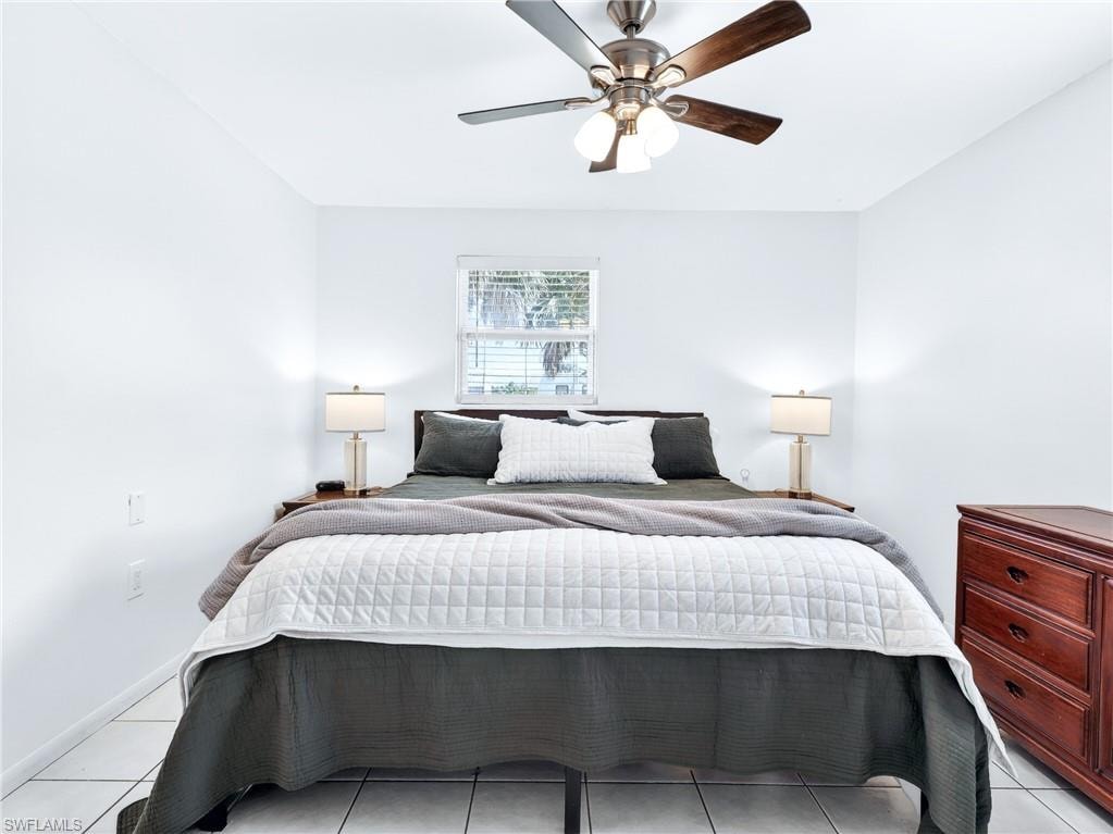 Bright room featuring a window with horizontal blinds, tiled flooring, and a ceiling fan with integrated lighting