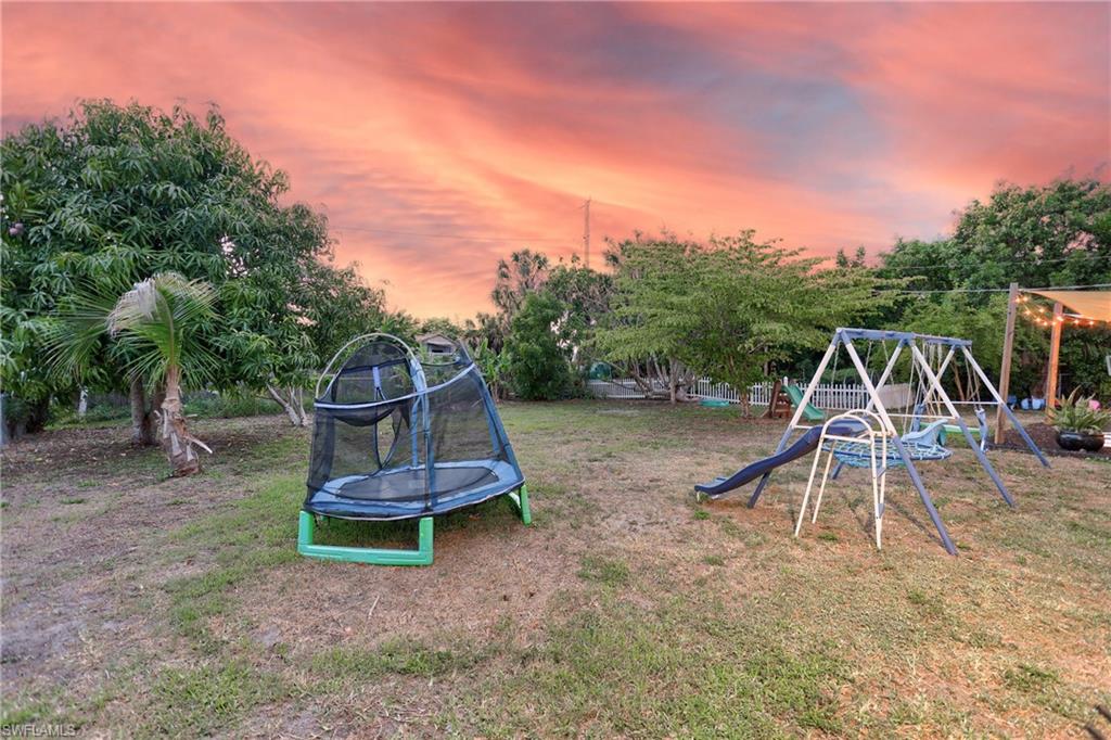 Expansive yard featuring mature trees and a swing set