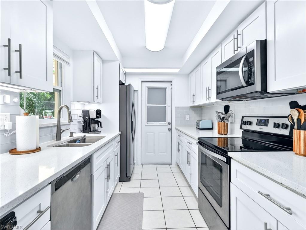 Bright kitchen featuring white shaker cabinetry, stainless steel appliances, light countertops, a tile backsplash, and tile flooring