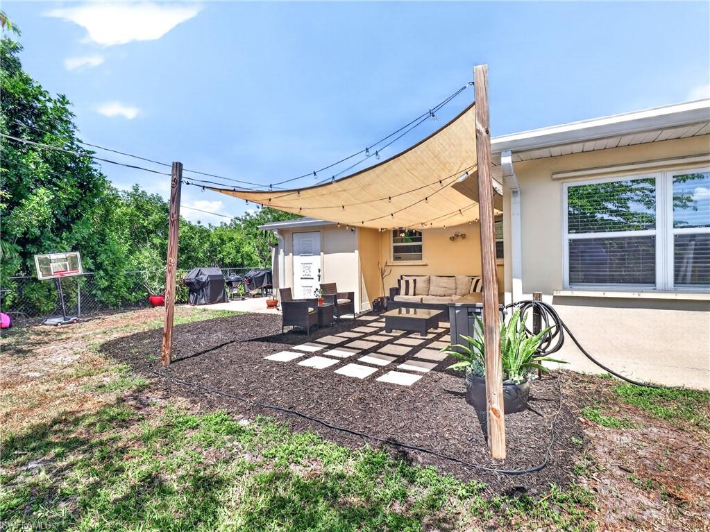 Outdoor patio featuring a light-colored shade sail, string lighting, and square paver stones