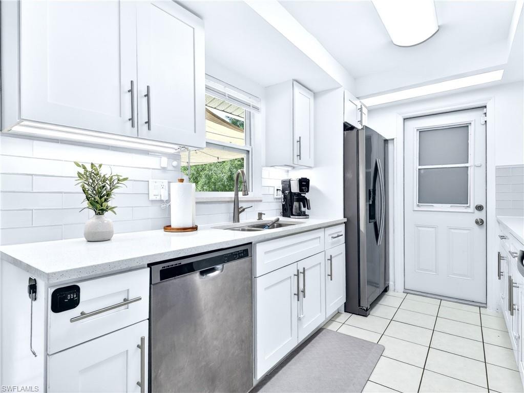 Bright kitchen featuring white shaker cabinetry with brushed nickel hardware, white subway tile backsplash, white countertops, and a stainless steel dishwasher