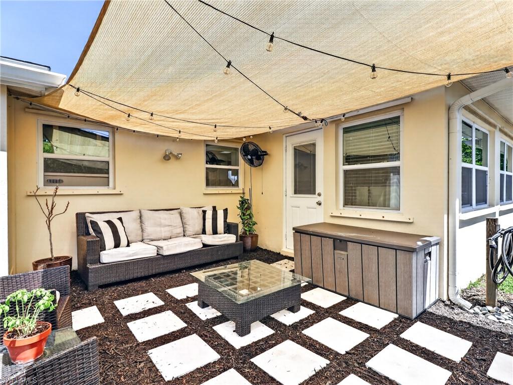 Outdoor patio featuring a shade sail canopy with string lights, square stepping stones, and a side-entry door