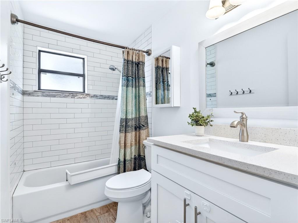 Bathroom featuring a white subway tile shower surround with an accent mosaic band, a built-in bathtub, and a window