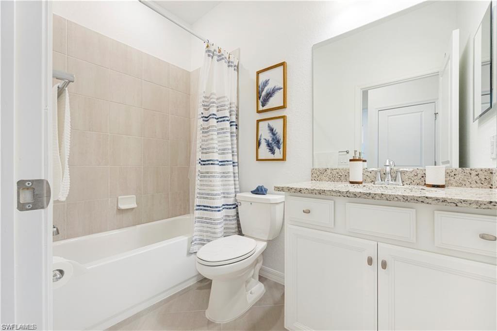 Bathroom featuring a white vanity with a light-colored countertop, an integrated sink, and an expansive wall mirror