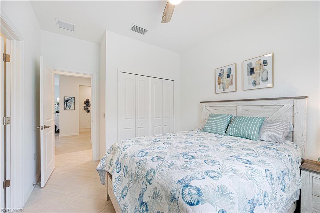 Bright interior space featuring a ceiling fan, white bi-fold closet doors, and light-toned tile flooring